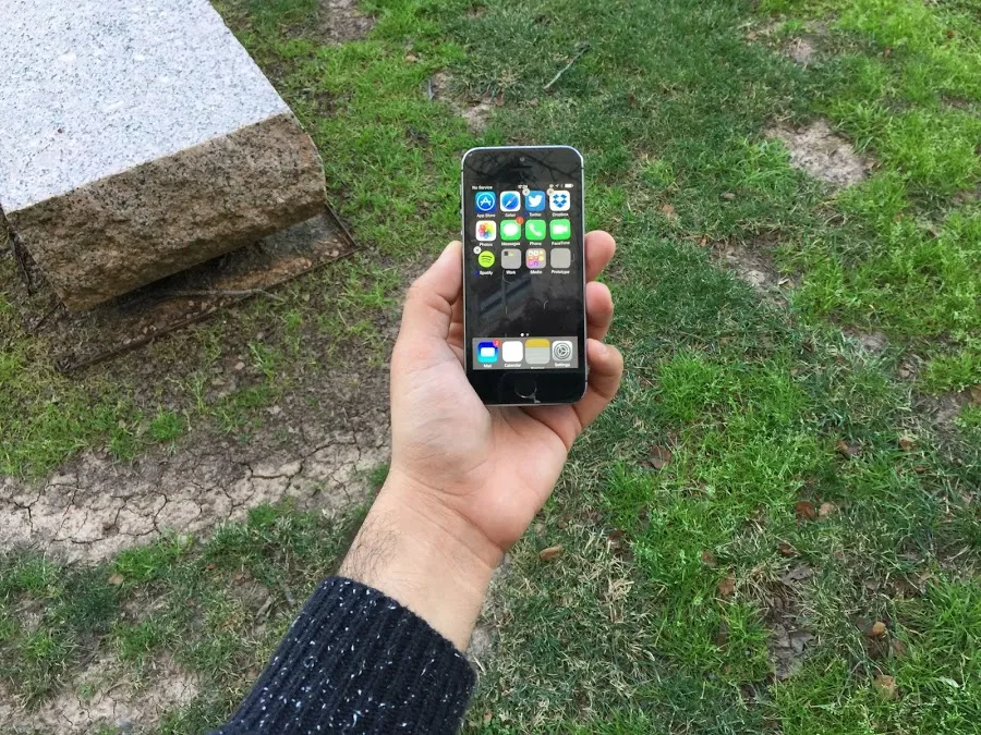 A photograph of an unlocked iPhone 5 in my hand, showing off a grid of apps.