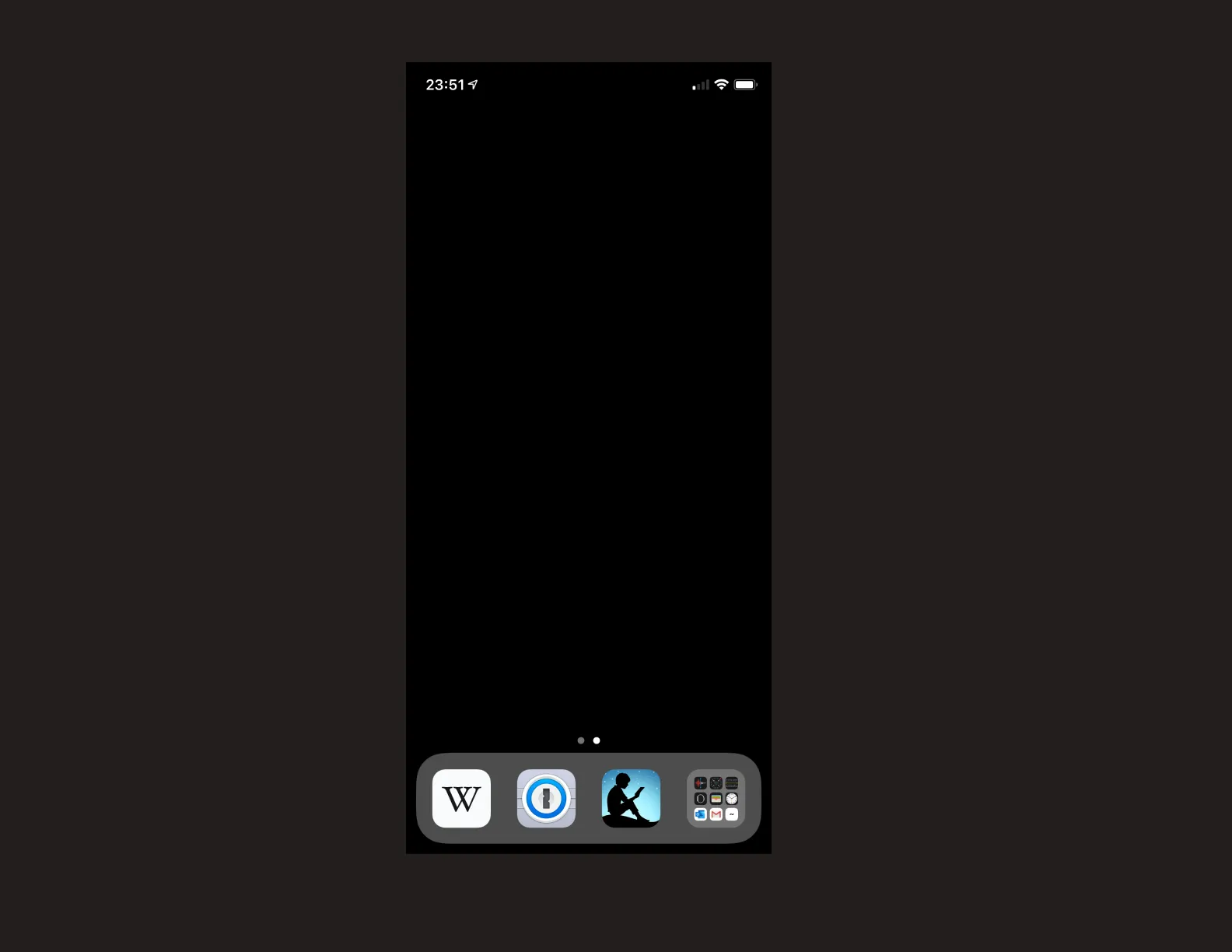 A screenshot of my iPhone's current main screen setup. It is blank besides the bottom four app shelf items: Wikipedia, 1Password, Kindle, and a folder of all other apps. The background of the main screen is pure black.