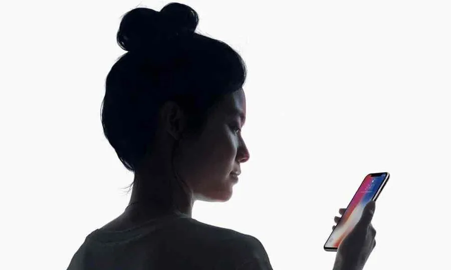 A screenshot of Apple's demonstration of FaceID phone unlocking. A woman is looking down at her iPhone.