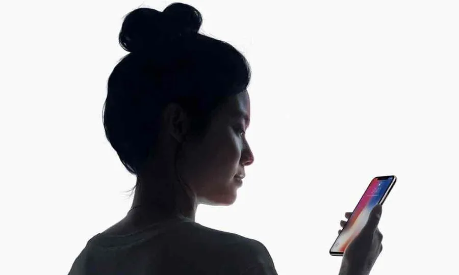 A screenshot of Apple’s demonstration of FaceID phone unlocking. A woman is looking down at her iPhone