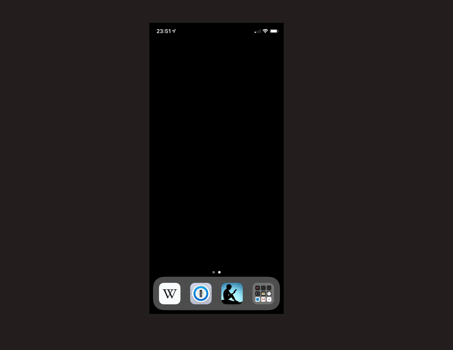 A screenshot of my iPhone’s current main screen setup. It is blank besides the bottom four app shelf items: Wikipedia, 1Password, Kindle, and a folder of all other apps. The background of the main screen is pure black.
